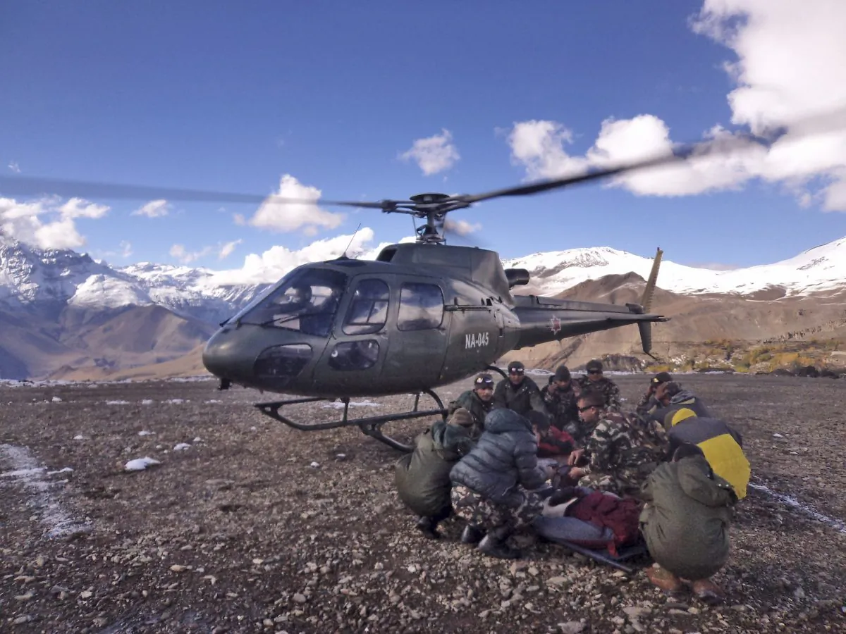 In this photo provided by the Nepalese army, soldiers prepare to airlift an avalanche victim in Thorong La pass area, Nepal, Wednesday, Oct. 15, 2014. An avalanche and blizzard in Nepal's mountainous north have killed at least 27 people, including eight foreign trekkers, officials said Wednesday. Five other climbers were hit by a separate avalanche on Mount Dhaulagiri and remain missing. (AP Photo/Nepalese Army)
