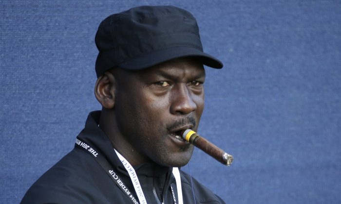 Basketball legend Michael Jordan smokes a cigar while watching the fourball match on the first day of the Ryder Cup golf tournament, at Gleneagles, Scotland, Friday, Sept. 26, 2014. (AP Photo/Matt Dunham)