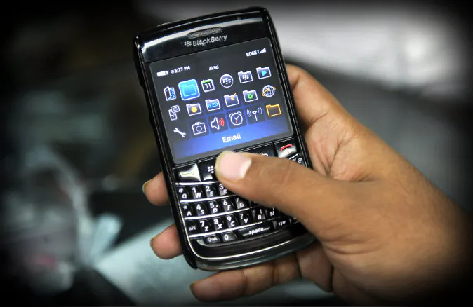 An Indian salesman checks a phone given for repairs at a Blackberry store in Mumbai on August 13, 2010. (Indranil Mukherjee/AFP/Getty Images; effects added by Epoch Times)
