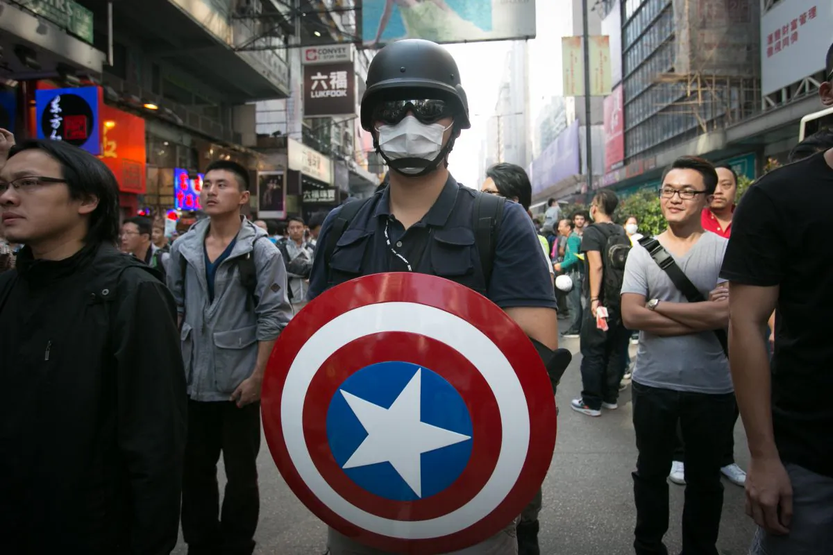 An  pro-democracy activist holds the Captain America sheild a few hours after the Hong Kong police removed all the barriers in the Monk Kok area on Oct. 17, 2014. U.S. government commission (CECC) examines China’s commitments to Hong Kong in light of recent pro-democracy protests. (Benjamin Chasteen/Epoch Times)