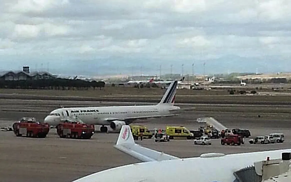 Emergency crews stand next to a plane, carrying 163 people, at the Madrid Airport, Spain, Thursday, Oct. 16, 2014. An Air France plane was isolated at Madrid's airport on Thursday because of a suspected Ebola case after a passenger was reported to have a fever and shivers, officials said. The passenger, who had traveled from Lagos, Nigeria, was taken by ambulance to an unspecified hospital in Madrid but the rest of the passengers were allowed to leave the plane as normal, Air France said in a statement. (AP Photo/Antoni Manchado)