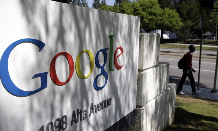 FILE - In this June 5, 2014 file photo, a man walks past a Google sign at the company's headquarters in Mountain View, Calif. Google reports quarterly financial results after the market closes Thursday, Oct. 16, 2014. (AP Photo/Marcio Jose Sanchez, File)