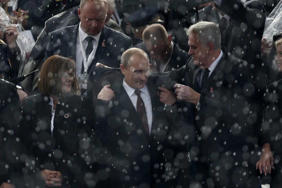 Serbian president Tomislav Nikolic (R) helps his Russian counterpart Vladimir Putin (C) to put on a jacket during a downpour at a military parade in Belgrade, Serbia, Thursday, Oct. 16, 2014. Greeted by enthusiastic chants of “Putin! Putin!,” Vladimir Putin attended a military parade Thursday in Slavic ally Serbia, where he held talks on economic issues, including on the South Stream gas pipeline opposed by the European Union. (AP Photo/Marko Drobnjakovic)