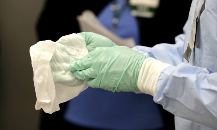 Registered nurse Keene Roadman, dressed in personal protective equipment, demonstrates bleach wiping the inner layer of gloves, after the outer gloves are removed during a training class at the Rush University Medical Center on Oct. 16, 2014, in Chicago. (AP Photo/Charles Rex Arbogast)