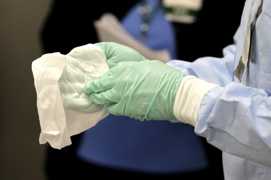 Registered nurse Keene Roadman, dressed in personal protective equipment, demonstrates bleach wiping the inner layer of gloves, after the outer gloves are removed during a training class at the Rush University Medical Center on Oct. 16, 2014, in Chicago. (AP Photo/Charles Rex Arbogast)