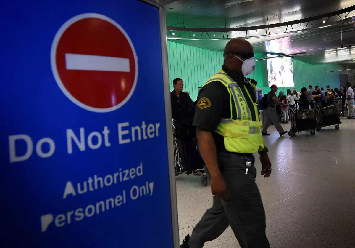 An airport worker wears a protective face mask in the arrivals area of the Los Angeles International Airport  on Oct. 9, 2014. (Mark Ralston/AFP/Getty Images)