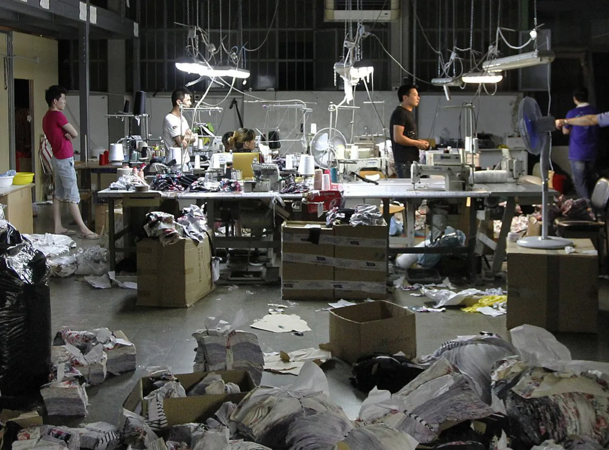 Chinese workers stand in a sequestered textile factory in Prato, Italy, on June 19, 2014. The compound, which had been divided into four different factories, was closed because of illegal bedrooms, too few fire extinguishers, no well-marked, easily accessible fire exits, no first aid kit and a dozen gas canisters found during the raid. Of the 44 workers at the factory, 35 were without proper contracts or social security contributions, and six did not have the legal right to stay in Italy. (AP Photo/Fabrizio Giovannozzi)