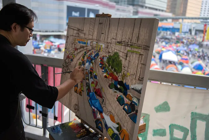 Hong Kong artist Perry Dino paints the pro-democracy protest area next to the central government offices in Hong Kong on October 14, 2014. (Alex Ogle/AFP/Getty Images)