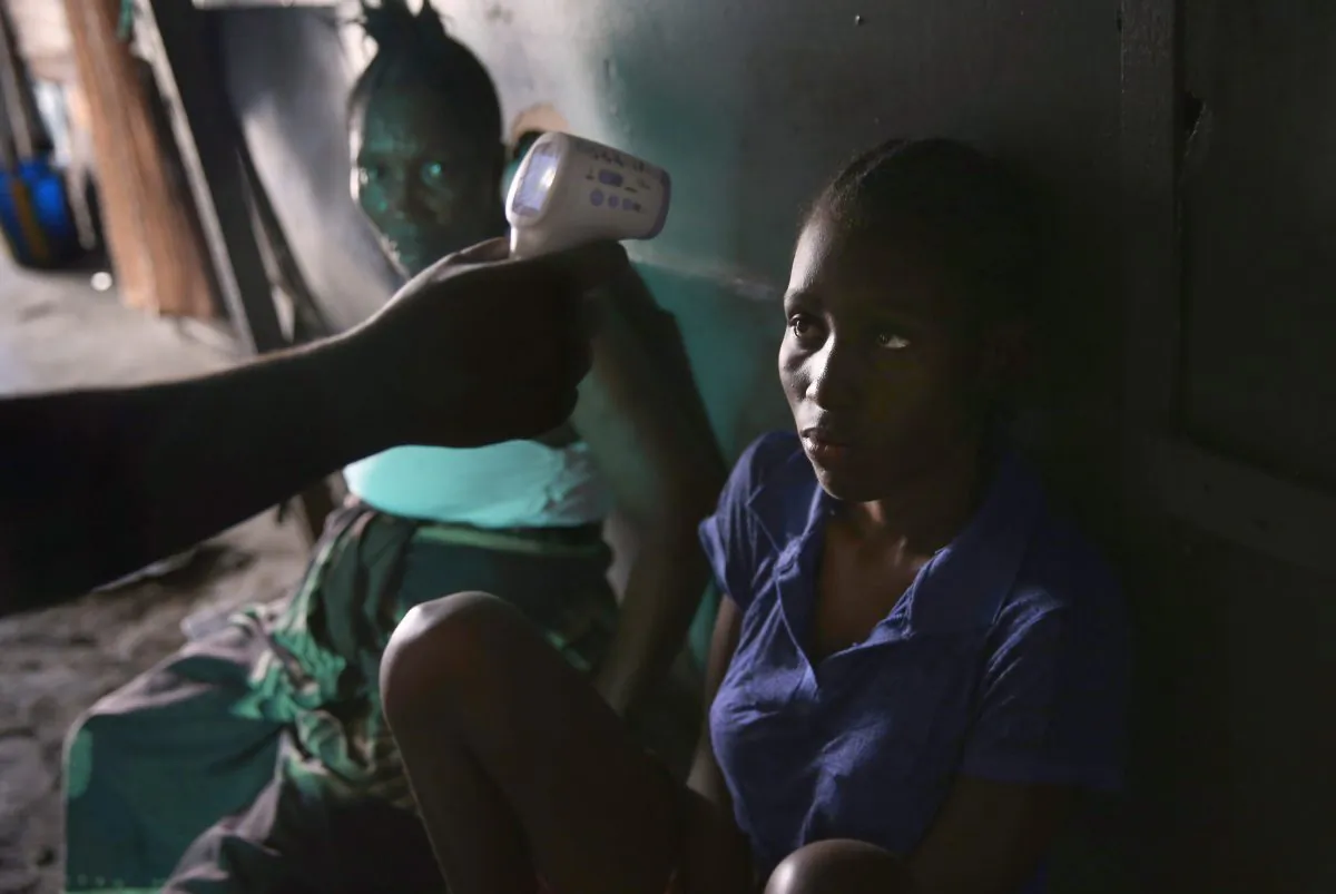 An Ebola tracing coordinator checks the temperature of Jessica Sompon, 17, finding her to have a fever in the West Point neighborhood in Monrovia, Liberia, on Oct. 17, 2014. (John Moore/Getty Images)