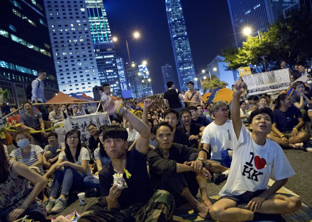 Pro-democracy protesters give thumbs down as they watch a live TV showing talks between Hong Kong government officials and students at an occupied area by the protesters outside the government headquarters in Hong Kong's Admiralty district,Tuesday, Oct. 21, 2014.  (AP Photo/Vincent Yu)