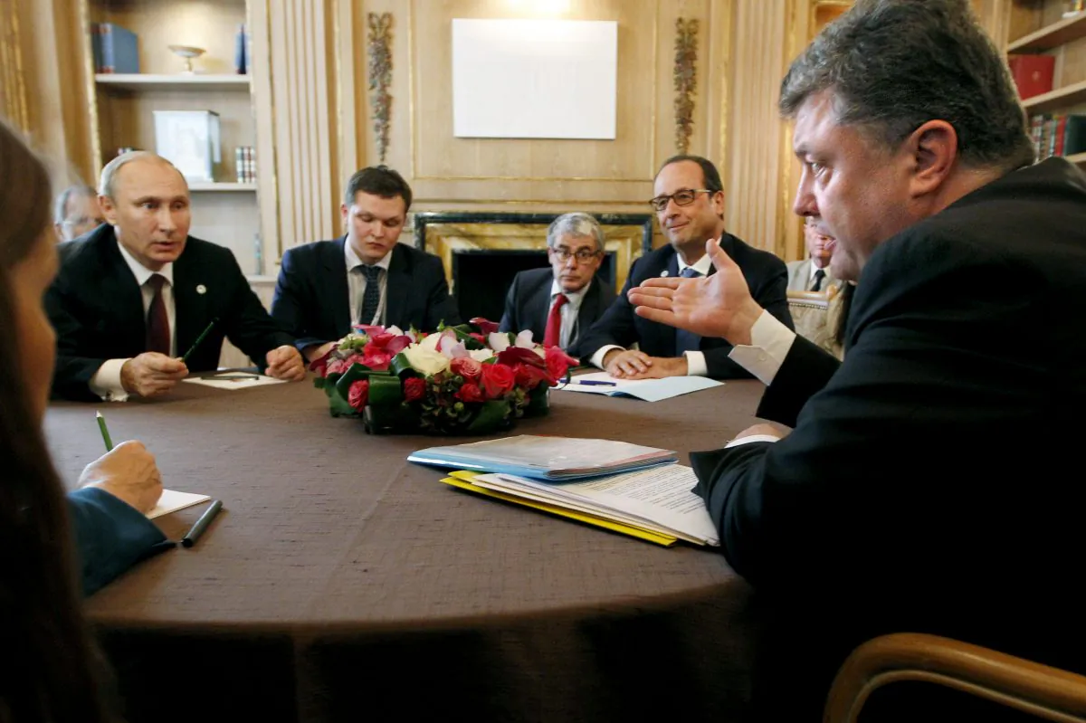 Ukrainian president Petro Poroshenko (R) talks with Russian President Vladimir Putin (L) as French President Francois Hollande listens during a meeting in Milan, Italy, Friday, Oct. 17, 2014. European leaders and Russia signaled cautious optimism over a peace deal for Ukraine after a high-level meeting in Milan on Friday, but emphasized details still need to be worked out. European leaders are pressing Russian leader Vladimir Putin to fully respect a cease-fire deal signed last month in Belarus, which has reduced by not completely ended hostilities in eastern Ukraine. (AP Photo/Luca Bruno)