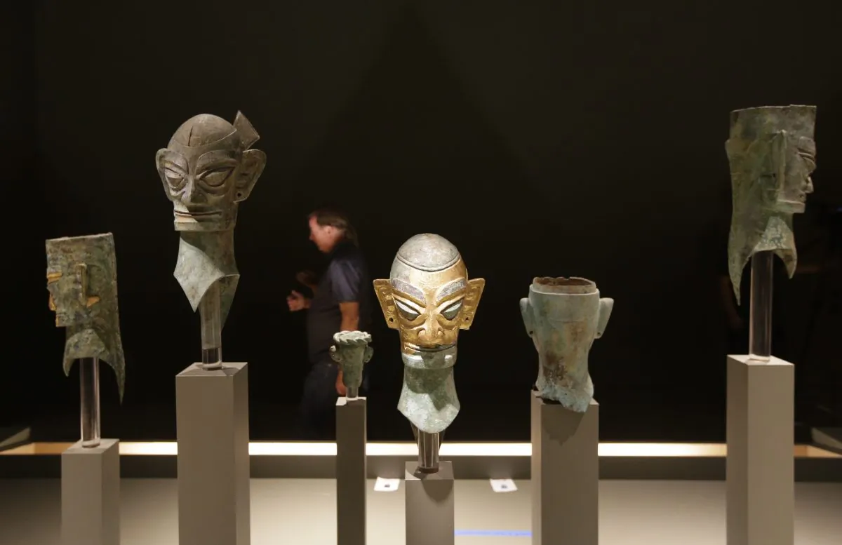A visitor to the Bowers Museum walks past a row of bronze masks, at the China’s Lost Civilization: The Mystery of Sanxingdui exhibit in Santa Ana, Calif. (AP Photo/Chris Carlson)