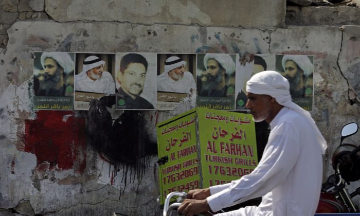 A Bahraini man cycles past images of jailed political activists in the western village of Malkiya, Bahrain, Oct. 15, 2014. PEN Canada has honoured jailed Saudi blogger Raif Badawi with its One Humanity Award. (AP Photo/Hasan Jamali)