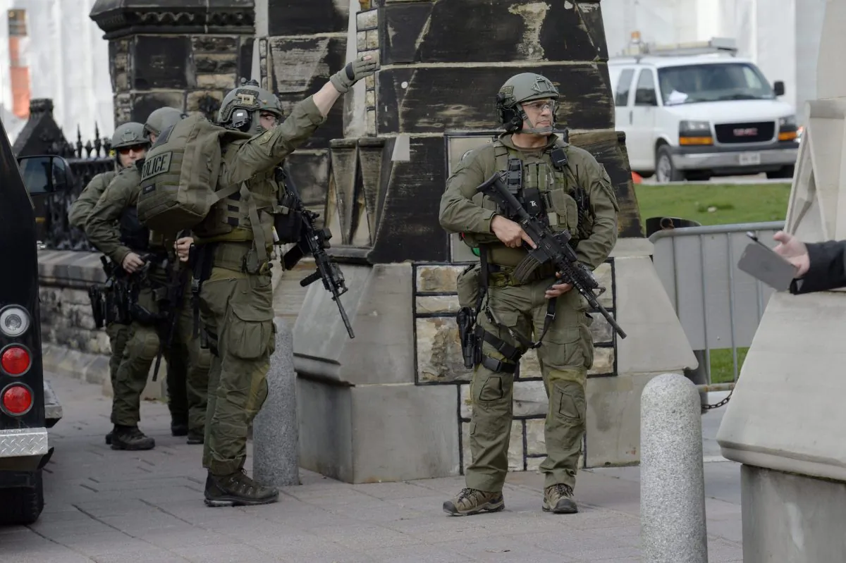 A Royal Canadian Mounted Police intervention team walks past a gate on Parliament hill in Ottawa Wednesday Oct. 22, 2014. A soldier standing guard at the National War Memorial has been shot by an unknown gunman and there have been reports of gunfire inside the halls of Parliament. Emergency responders are still on the scene as paramedics performed CPR on the soldier before he was taken away by ambulance. (AP Photo/The Canadian Press, Adrian Wyld)