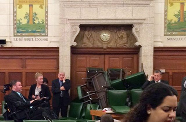 In this photo provided by Conservative MP Nina Grewal, members of Parliament barricade themselves in a meeting room on Parliament Hill in Ottawa, Canada, Wednesday, Oct. 22, 2014, after shots were fired in the building. A gunman with a scarf over his face shot to death a Canadian soldier standing guard at the nation's war memorial Wednesday, then stormed Parliament in a hail of gunfire before he was killed by the usually ceremonial sergeant-at-arms, authorities and witnesses said. (AP Photo/The Canadian Press, Nina Grewal)
