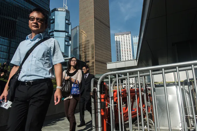 Civil servants walk past a barricade set up and reopened by pro-democracy protestors near the government headquarters as they return to work in Hong Kong on October 6, 2014. Hong Kong has been plunged into the worst political crisis since its 1997 handover as pro-democracy activists take over the streets following China's refusal to grant citizens full universal suffrage. (Anthony Wallace/AFP/Getty Images)