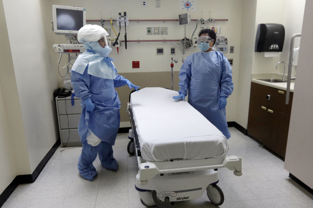 FILE - In this Oct. 8, 2014, file photo, Bellevue Hospital nurse Belkys Fortune, left, and Teressa Celia, Associate Director of Infection Prevention and Control, pose in protective suits in an isolation room, in the Emergency Room of the hospital, during a demonstration of procedures for possible Ebola patients in New York. A doctor who recently returned to New York City from West Africa is being tested for the Ebola virus. The doctor had a fever and gastrointestinal symptoms and was taken Thursday to Manhattan's Bellevue Hospital. (AP Photo/Richard Drew, File)