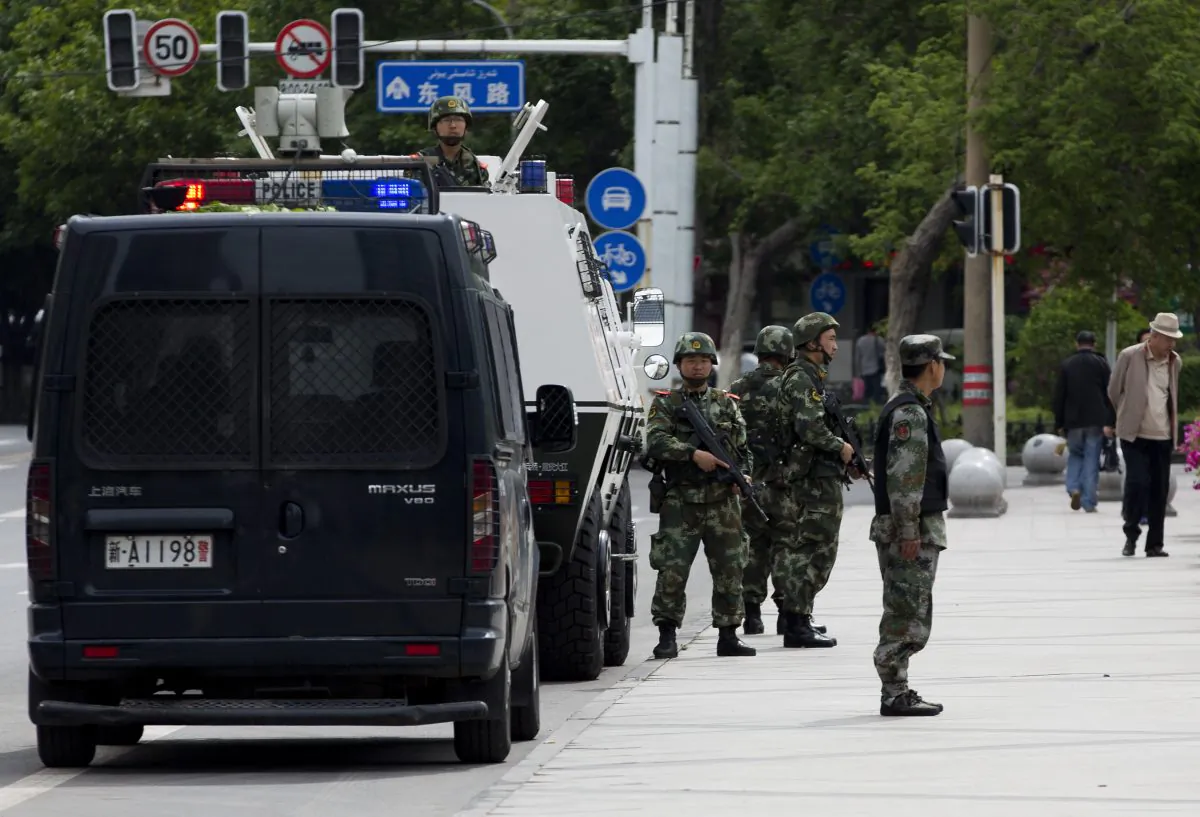 In this Friday, May 23, 2014 photo, armed Paramilitary policemen stand guard next to their Armored personnel carrier parked near the People's Square in Urumqi, in China's northwestern province of Xinjiang. A human rights group says 100,000 Chinese troops are headed to the restive province. (AP Photo/Andy Wong) 