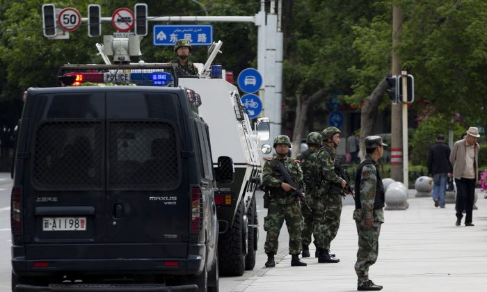 In this Friday, May 23, 2014 photo, armed Paramilitary policemen stand guard next to their Armored personnel carrier parked near the People's Square in Urumqi, in China's northwestern province of Xinjiang. A human rights group says 100,000 Chinese troops are headed to the restive province. (AP Photo/Andy Wong) 