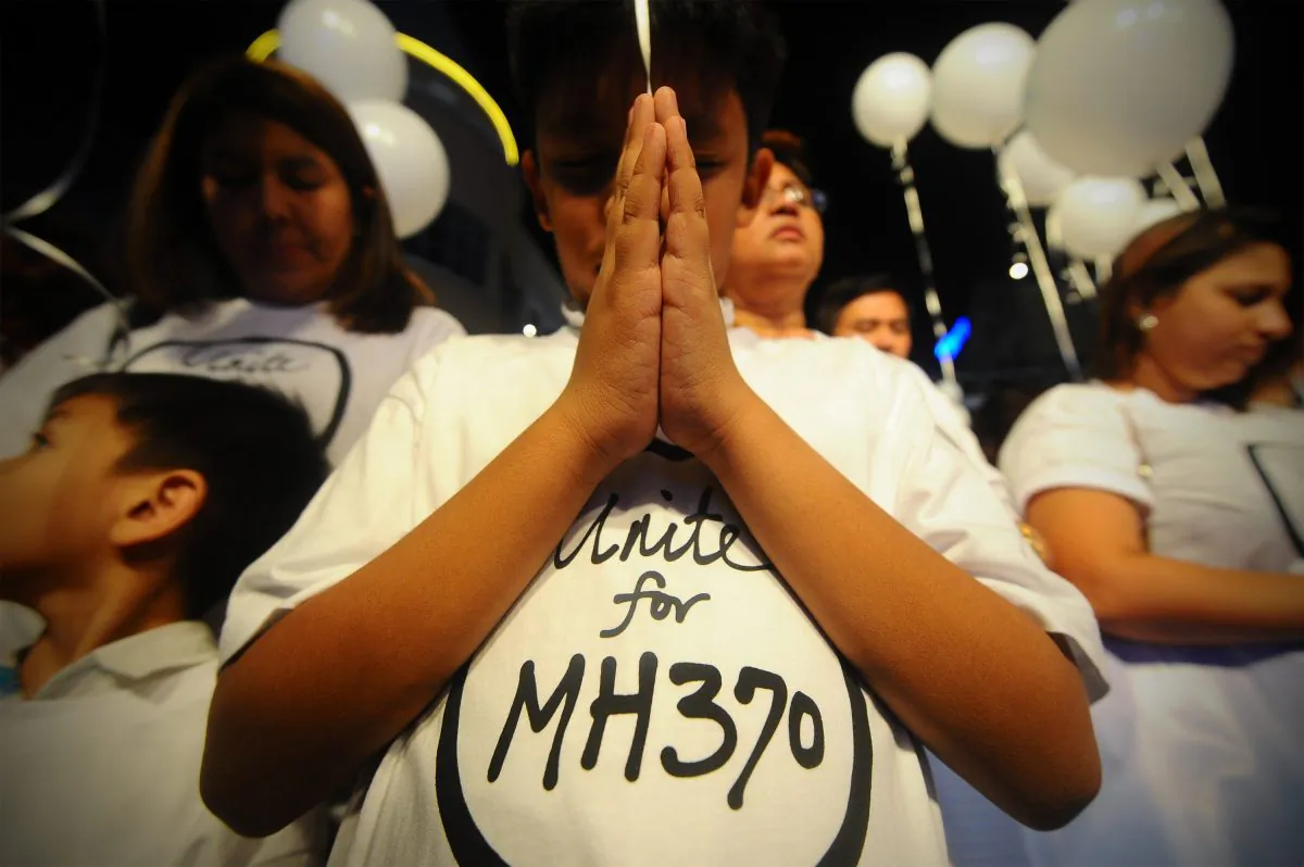 A young Malaysian boy prays, at an event for the missing Malaysia Airline Flight 370, at a shopping mall, in Petaling Jaya, on the outskirts of Kuala Lumpur, Malaysia, March 18, 2014. (AP Photo/Joshua Paul, File)