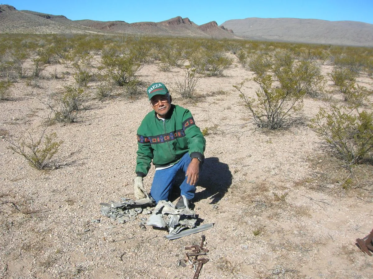 Coyame resident Leandro Valeriano examines debris from the crash of a small plane in the Chihuahuan Desert just north of Coyame, Mexico. The debris may been part of the air plane that allegedly collided with a UFO at high speeds in 1974. The allegations continue that the U.S. government destroyed all remaining evidence with high yield explosives. (Wikimedia Commons)