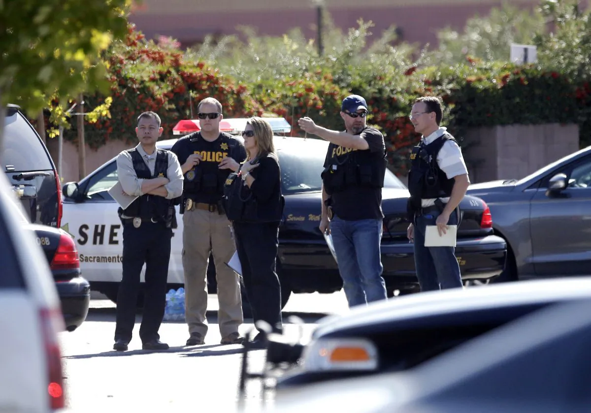 Law enforcement officers gather at the site where a Sacramento County Sheriff's deputy was shot by an assailant who then carjacked two vehicles prompting a manhunt in Sacramento, Calif., Friday, Oct. 24, 2014. (AP Photo/Rich Pedroncelli)