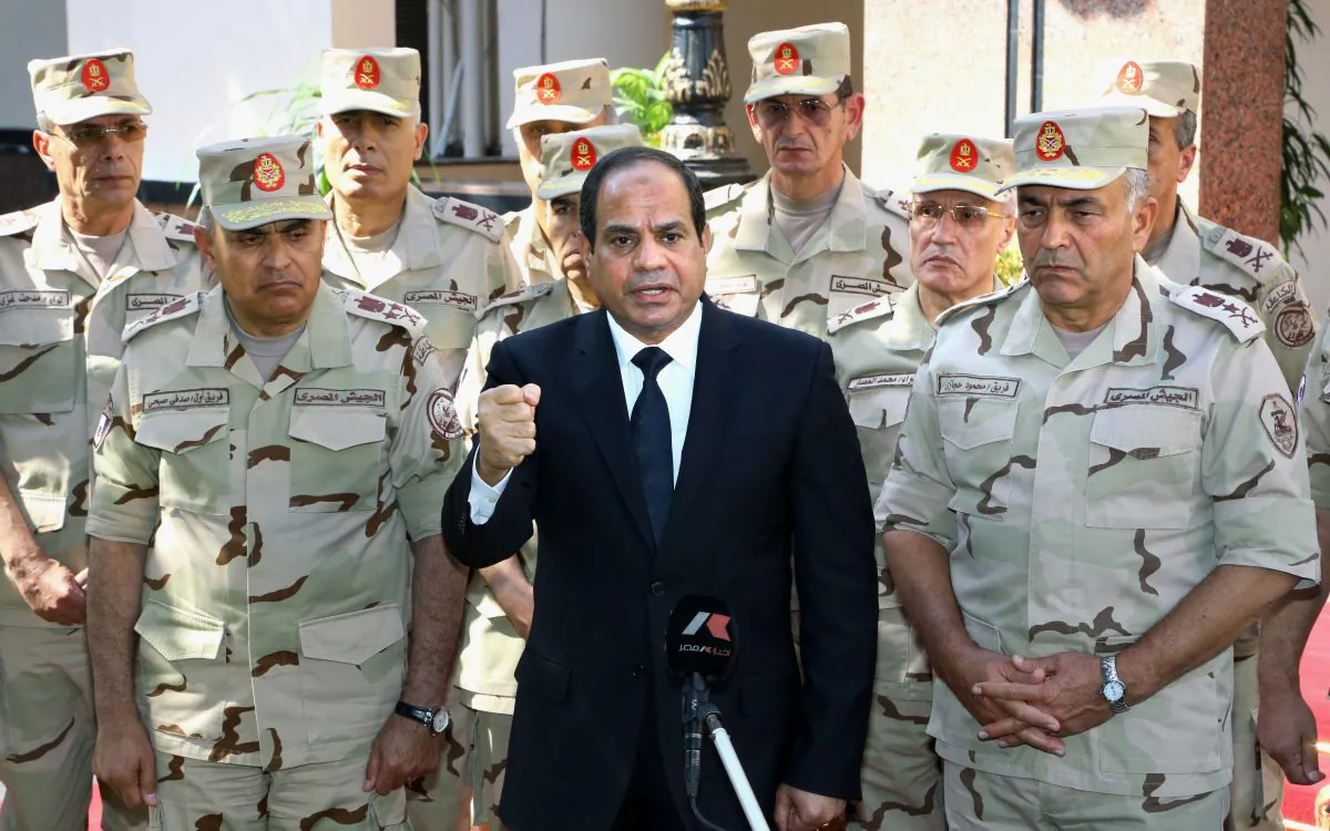 Egyptian President Abdel-Fattah el-Sissi (C) speaks in front of the state-run TV ahead of a military funeral for troops killed in an assault in the Sinai Peninsula, as he stands with army commanders in Cairo, Egypt, Saturday, Oct. 25, 2014. El-Sissi appeared on the state-run TV and said a deadly assault on an army checkpoint in the Sinai Peninsula that killed 30 troops was a "foreign-funded operation." No group has yet claimed responsibility for the attack. (AP Photo/MENA, Mohammed Samaha)