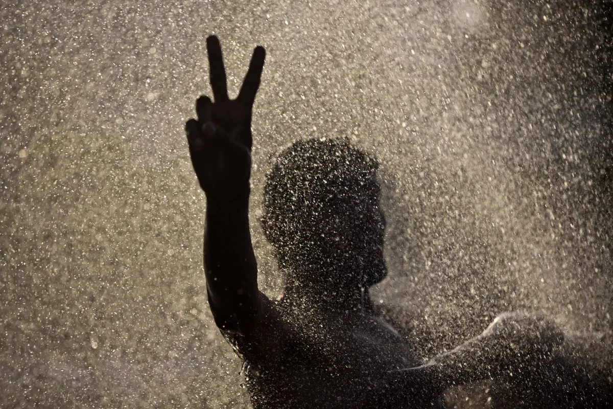 Anti-government protester flashes the victory sign amid splashing water from a broken water pipe near the parliament building where he and others are camping in Islamabad, Pakistan, on Sept. 22, 2014. It had all the elements of a classic coup: thousands descending on the capital, clashing with police outside parliament and commandeering state TV to demand the ouster of a civilian leader who had locked horns with the military in a country with a long history of turmoil and dictatorship. But when the tear gas cleared in Islamabad in August, Pakistans Prime Minister Nawaz Sharif remained in office with the support of the entire parliament, the troops were still in their barracks, and the protesters had dwindled to a few thousand, their revolution confined to a festive, shrinking tent camp. (AP Photo/Muhammed Muheisen)