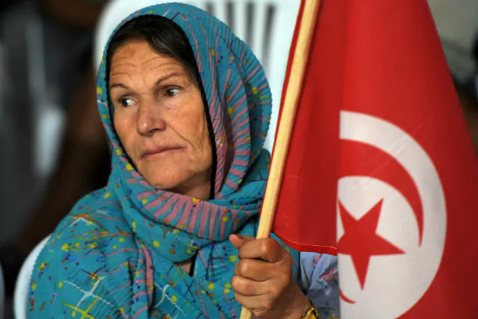 A woman in Tunisia holds the national flag during a meeting of the former prime minister, Hamed Karaouihis, as he campaigns in Menzel Temim on Oct. 18, 2014. (Fethi Belaid/AFP/Getty Images)