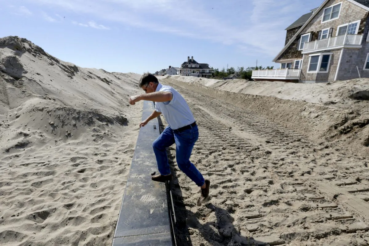 Chris Niebling, deputy operation chief of the Office of Emergency Management in Mantoloking, N.J., Oct. 9, 2014. Niebling steps over construction of the new seawall while giving a tour of the construction. After Superstorm Sandy, New York and New Jersey officials vowed to make sure the unprecedented destruction wouldn’t happen again. (AP Photo/Julio Cortez)