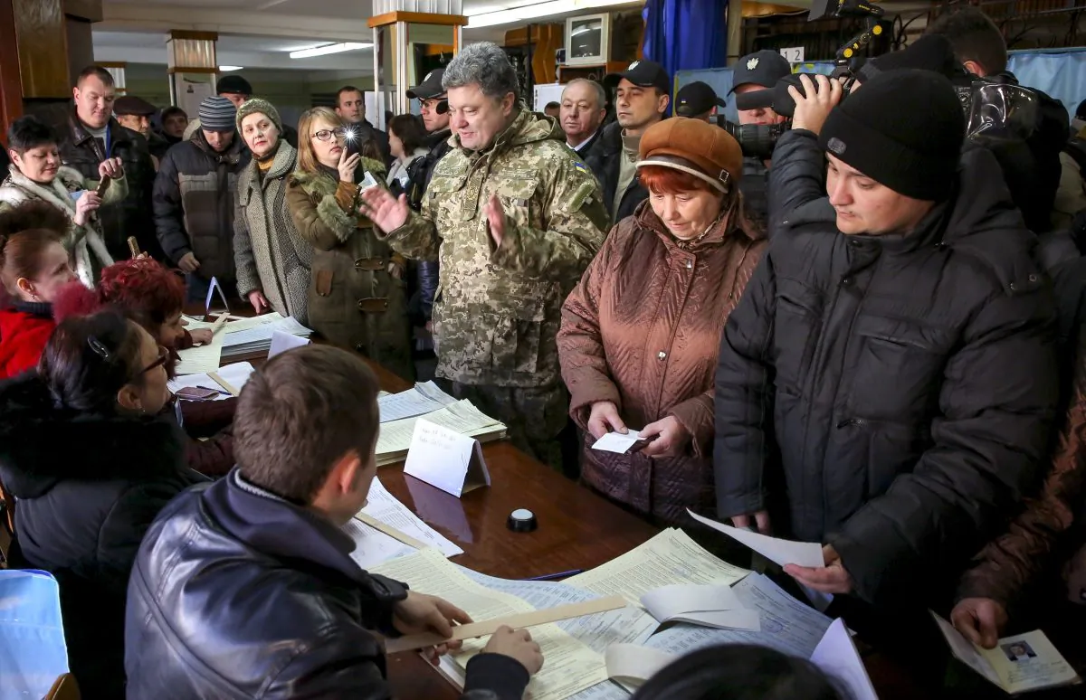 Ukrainian President Petro Poroshenko (C) speaks with local staff at a poling station during voting in parliamentary elections in Kramatorsk, Donetsk region, Ukraine, Sunday, Oct. 26, 2014. Voters in Ukraine headed to the polls Sunday to elect a new parliament, overhauling a legislature tainted by its association with ousted President Viktor Yanukovych. (AP Photo/Mikhail Palinchak)