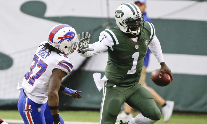 New York Jets quarterback Michael Vick (1) stiff arms Buffalo Bills' Nickell Robey (37) during the second half of an NFL football game, Sunday, Oct. 26, 2014, in East Rutherford N.J. The Bills won the game 43-23. (AP Photo/Seth Wenig)