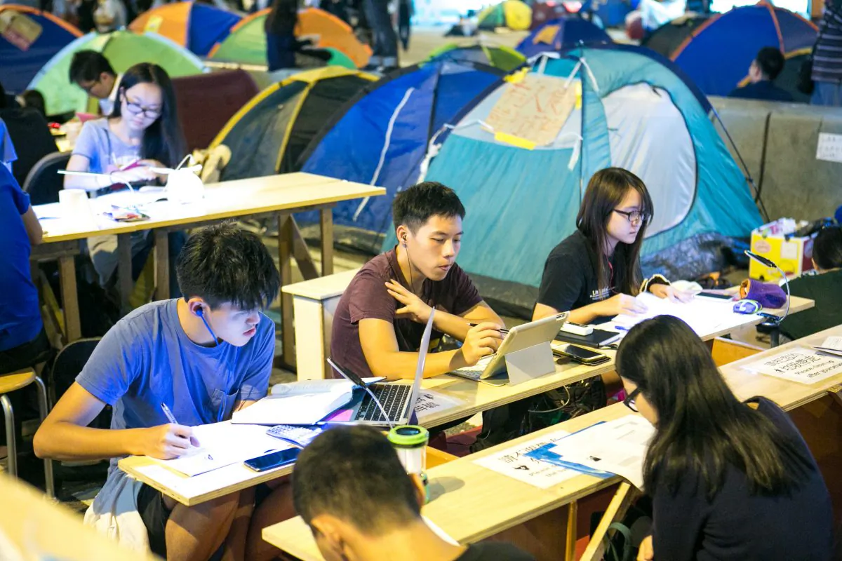 Students work at what is called the "Study Corner," which was set up by a few activists so students can still do their homework and study while protesting at the same time in the Central District of Hong Kong on Oct. 14, 2014. The study has a generator which provides electricity and also working WiFi for the students. (Benjamin Chasteen/Epoch Times)