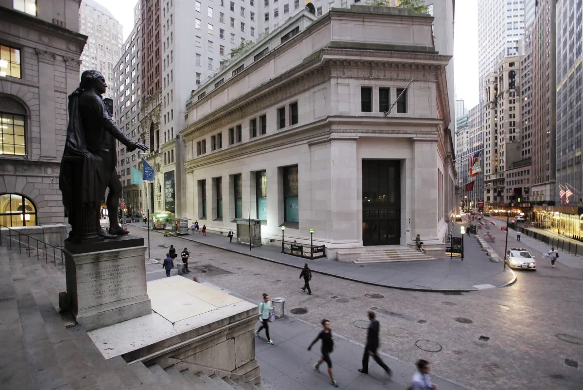 People walk to work on Wall Street beneath a statue of George Washington in New York on Oct. 8, 2014. US stocks rose early Tuesday, Oct. 28, 2014, as investors weighed earnings reports from several companies and awaited news from a two-day US Federal Reserve meeting that ends tomorrow. (AP Photo/Mark Lennihan)
