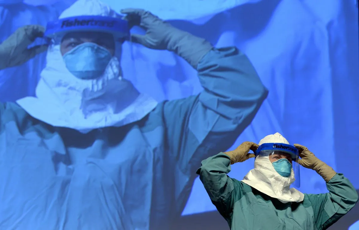 Barbara Smith, a nurse at Mount Sinai Health Systems and a CDC official demonstrate the proper technique for donning protective gear during an Ebola educational session for healthcare workers at the Jacob Javits Center in New York, Oct. 21, 2014. (Timothy A. Clary/AFP/Getty Images)