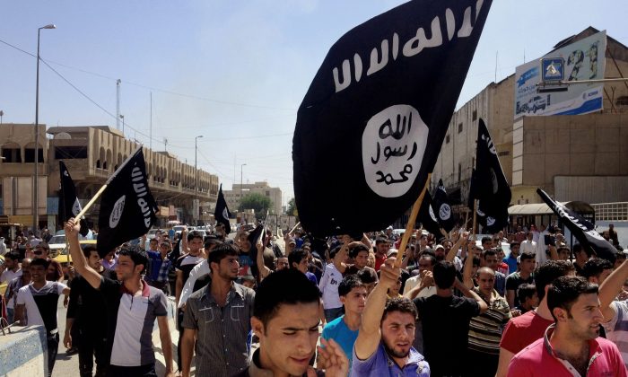  In this June 16, 2014 file photo, demonstrators chant pro-Islamic State group slogans as they carry the group's flags in front of the provincial government headquarters in Mosul. (AP Photo)