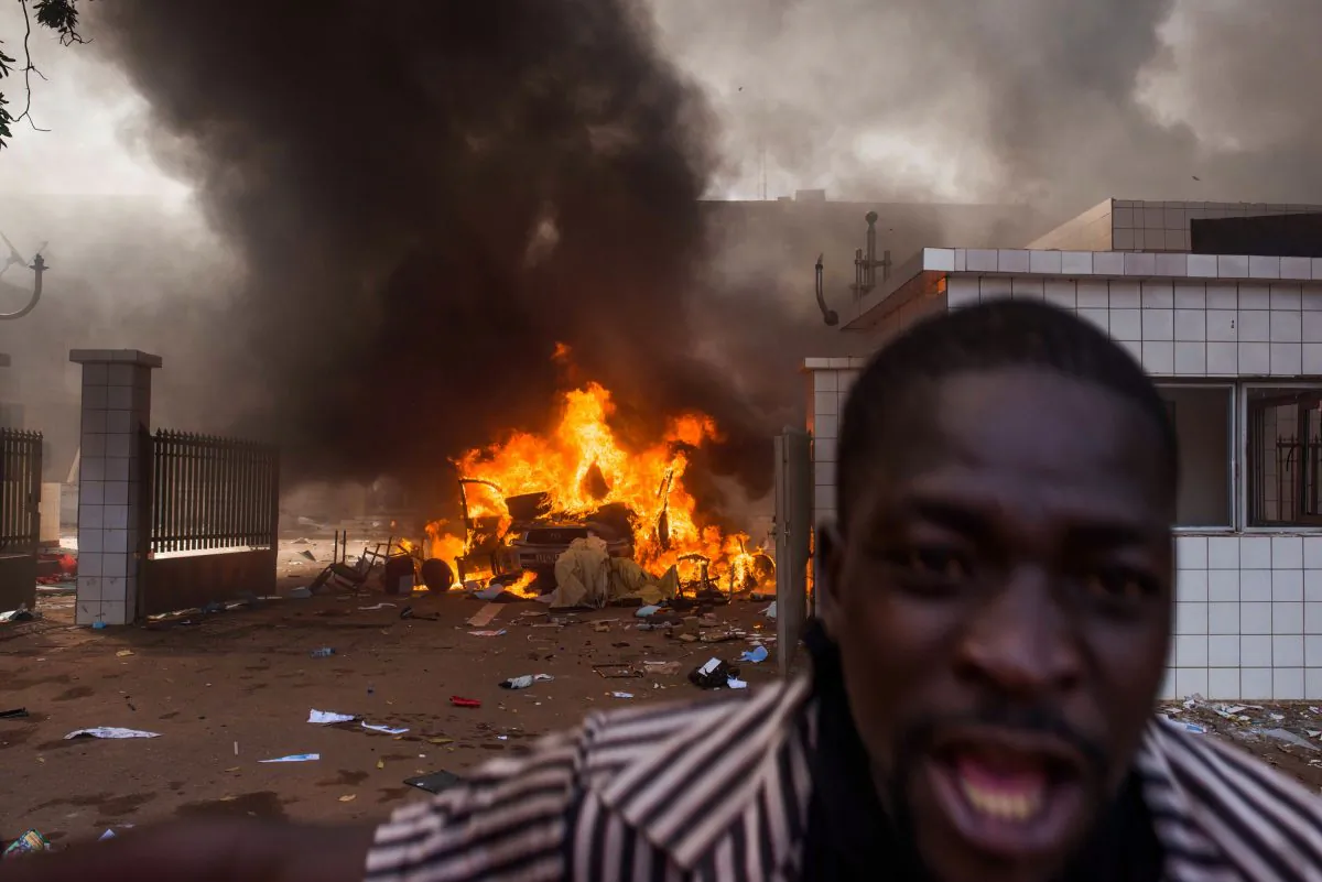 A car burns outside the parliament building in Burkina Faso as people protest  against their longtime president  Blaise Compaore who is  seeking another term in Ouagadougou, Burkina Faso, Thursday, Oct. 30, 2014. Protesters stormed Burkina Faso’s parliament Thursday, dragging furniture and computers onto the street and setting the main chamber ablaze, in the most significant challenge to the president’s rule during his 27 years in power.(AP Photo/Theo Renaut)