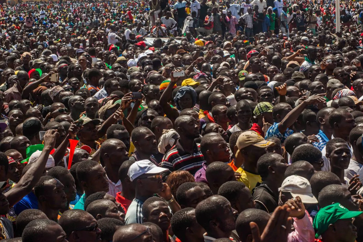 People gather near a government building as they await the announcement of a new interim leader in Ouagadougou, Burkina Faso, Friday, Oct. 31, 2014. An army general stepped into the vacuum left in Burkina Faso on Friday by the resignation President Blaise Compaore, who ended his 27-year reign under pressure from violent protests. (AP Photo/Theo Renaut)