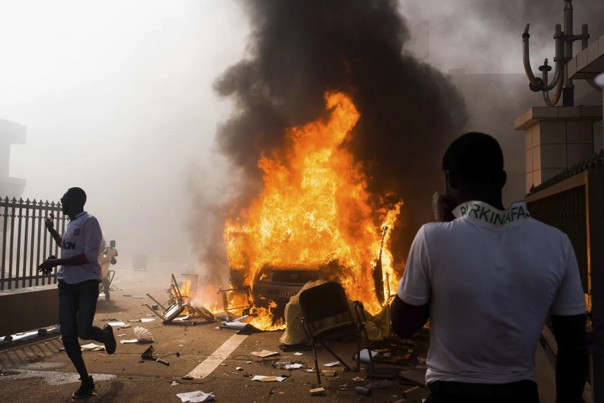 In this photo taken Thursday, Oct. 30, 2014, a car burns after being set alight by protesters outside the parliament building in Burkina Faso as people protest against their longtime President Blaise Compaore who seeks another term, in Ouagadougou, Burkina Faso. Protesters stormed Burkina Faso’s parliament Thursday, dragging furniture and computers onto the street and setting the main chamber ablaze, in the most significant challenge to the president’s rule during his 27 years in power. (AP Photo/Theo Renaut)