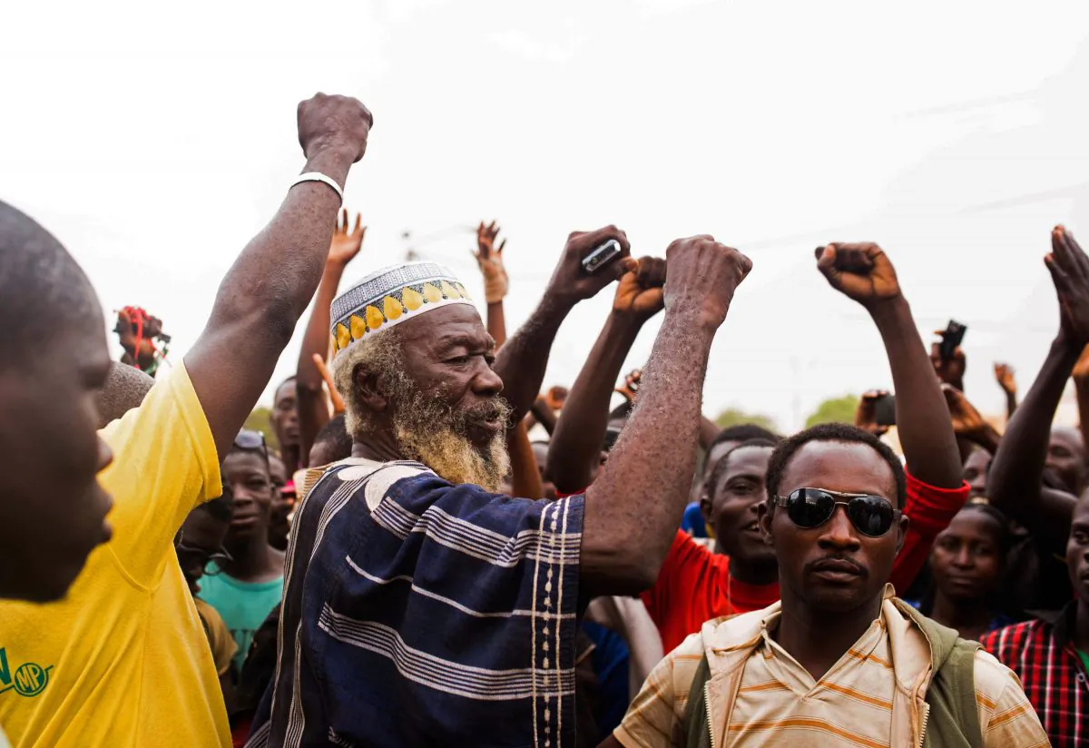 Anti government political leader Boukari Kabore, center, among anti government protestors in Burkina Faso after the announcement of a new interim leader,  Gen. Honore Traore,  in Ouagadougou, Burkina Faso, Friday, Oct. 31, 2014. The president of Burkina Faso stepped down Friday after protesters stormed parliament and set the building ablaze, ending the 27-year reign of one of Africa's longest-serving rulers who had survived previous attempts to topple him. (AP Photo/Theo Renaut)