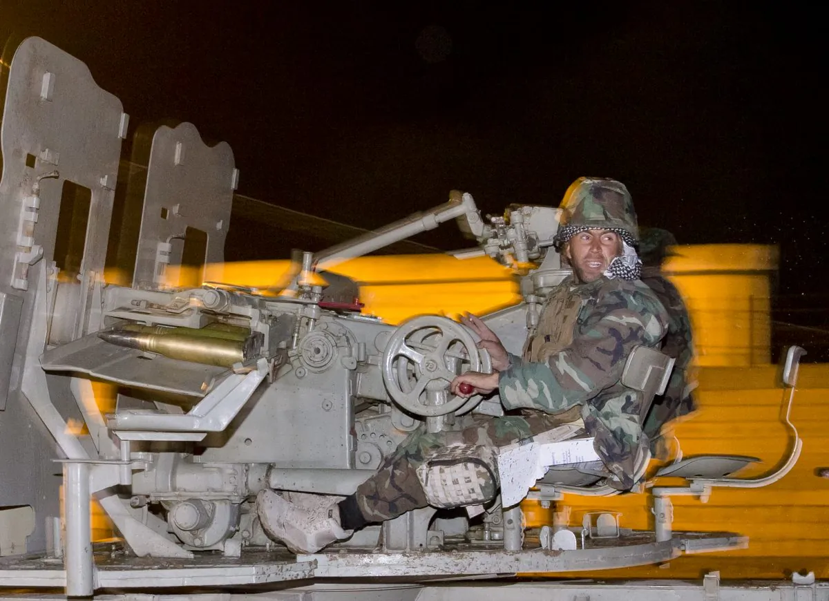 An Iraqi Kurdish peshmerga fighter rides on an artillery weapon as he leaves the outskirts of Suruc, Turkey, towards the Turkey-Syria border, on the way to the Syrian city of Kobani, Friday, Oct. 31, 2014. The 10 peshmerga fighters from Iraq who entered the embattled northern Syrian town of Kobani one day earlier returned to Turkey Friday to prepare for their forces' full deployment, and a senior Kurdish official blamed Ankara for the delay. (AP Photo/Vadim Ghirda)