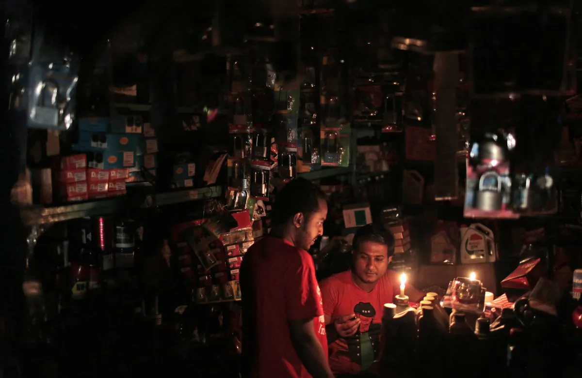 A Bangladeshi salesman interacts with a customer during a blackout in Dhaka, Bangladesh, Saturday, Nov. 1, 2014. (A.M. Ahad/AP Photo)