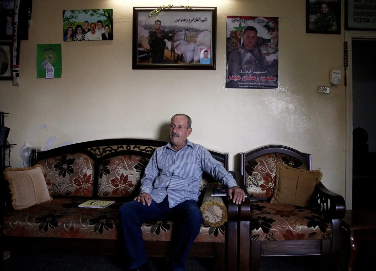 Ramadan Haidar, father of Mahmoud, a 23-year-old Syrian who was killed while fighting in the military, sits in his living room under photos of his son, in the city of Tartous, the capital of a coastal province in Syria on Oct. 28, 2014. (AP Photo/Diaa Hadid)
