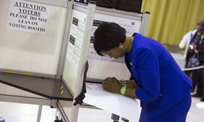 Washington Democratic mayoral candidate Muriel Bowser, right, fills out her ballot on election day at LaSalle-Backus Education Campus, on Tuesday, Nov. 4, 2014, in Washington. Bowser is favored to continue her party's unbeaten streak for the city's top office in Tuesday's election. (AP Photo/Evan Vucci)