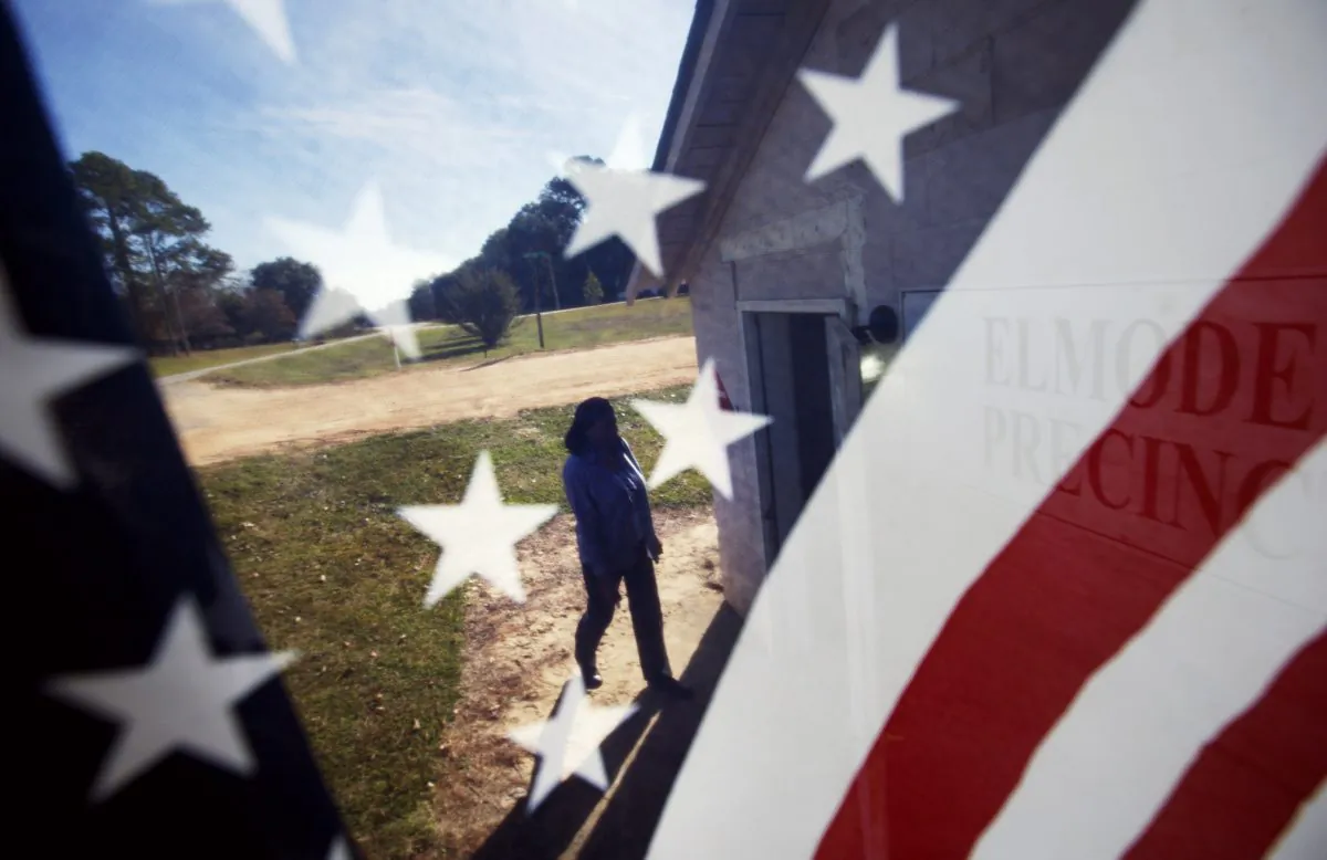 Woman is seen through an American flag as she walks into the Elmodel precinct to cast her ballot, Tuesday, Nov. 4, 2014, in Elmodel, Ga. (AP Photo/David Goldman)