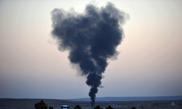 Thick smoke rises from the Syrian town of Kobani as Turkish soldiers stand guard on the Turkish side of the border during fighting between ISIL militants and Kurdish People's Protection Unit forces, as seen from the Mursitpinar crossing on the Turkish-Syrian border on Oct 26, 2014. Since mid-September, more than 200,000 people from Kobani have fled into Turkey. (Kutluhan Cucel/Getty Images)