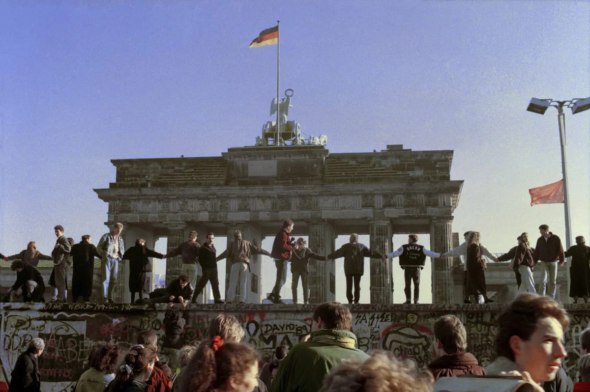 This Nov. 10, 1989 file photo shows Berliners singing and dancing on top of The Berlin Wall in celebration of the opening of the East German-West German border. (AP Photo/Thomas Kienzle)
