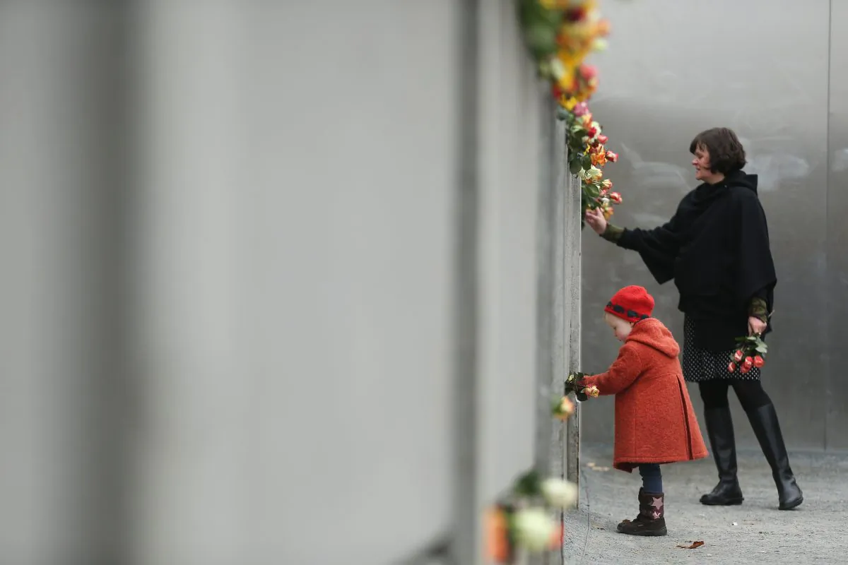 Hulda, 3, places flowers in between slats of the former Berlin Wall at the Berlin Wall Memorial at Bernauer Strasse on the 25th anniversary of the fall of the Wall on November 9, 2014 in Berlin, Germany. (Sean Gallup/Getty Images)