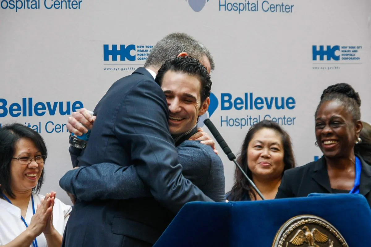 Dr. Craig Spencer (R) hugs New York City Mayor Bill de Blasio at a press conference in the lobby of Bellevue Hospital, Manhattan, New York, on Nov. 11, 2014. Spencer, who contracted Ebola while volunteering in Guinea, West Africa, was released after being cured from the deadly disease. (Epoch Times)