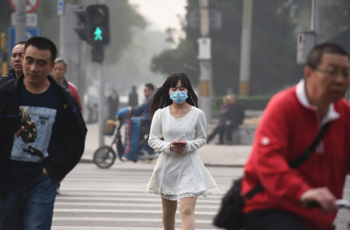 A woman wears a mask on a polluted day in Beijing on Oct. 20, 2014. Beijing resumed normal life after the APEC meetings closed on Nov. 12, 2014, as detained petitioners were released, heat was supplied, factory operations resumed, and car restrictions were lifted, and so on. (Greg Baker/AFP/Getty Images)